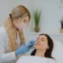 Zabieg wolumetrii twarzy w MS Aesthetic Clinic. Specjalistka wykonuje iniekcje kwasem hialuronowym w okolice policzka.