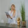 Specjalistka MS Aesthetic Clinic przy recepcji z tabletem. Nowoczesne, eleganckie wnetrze kliniki.